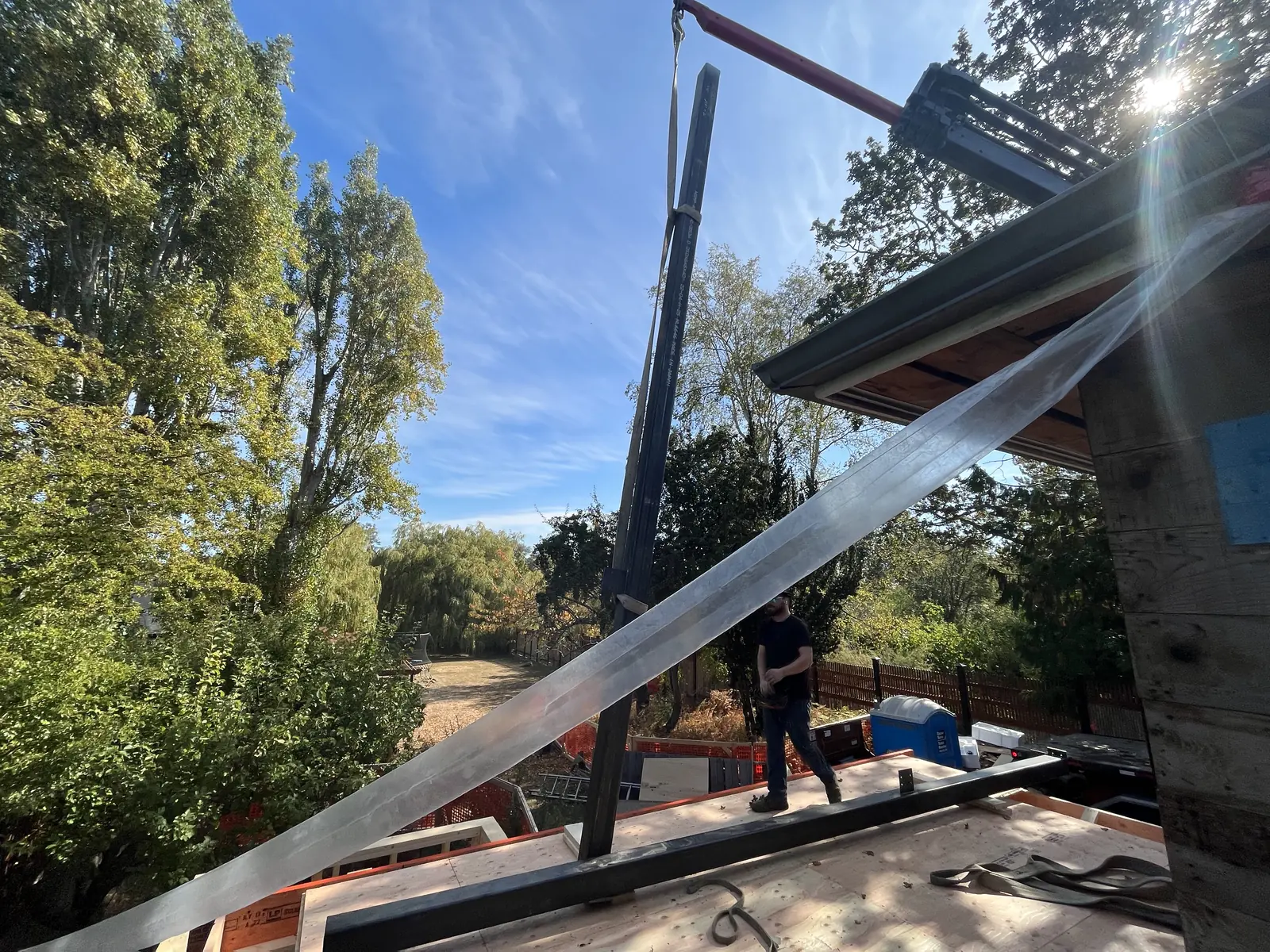 Steel beam being craned into position against a clear sky