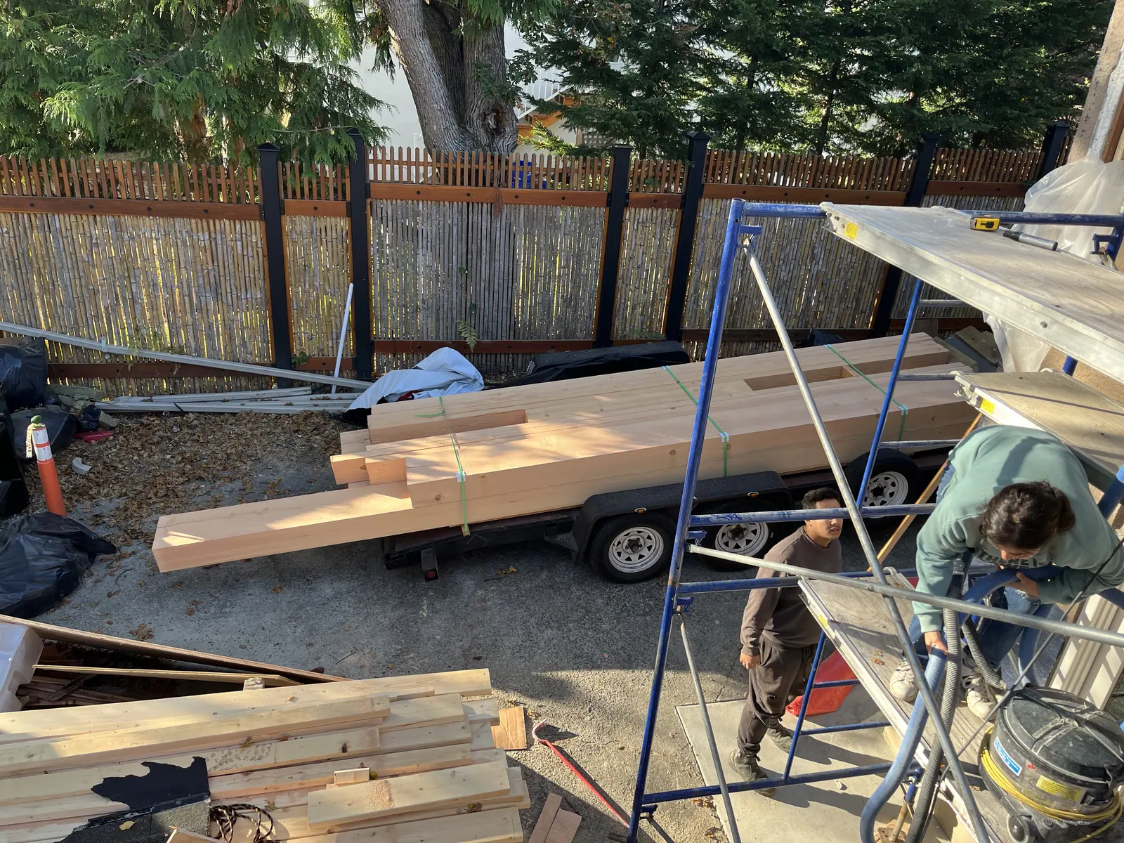 Timber being cut on site beside stacked framing lumber