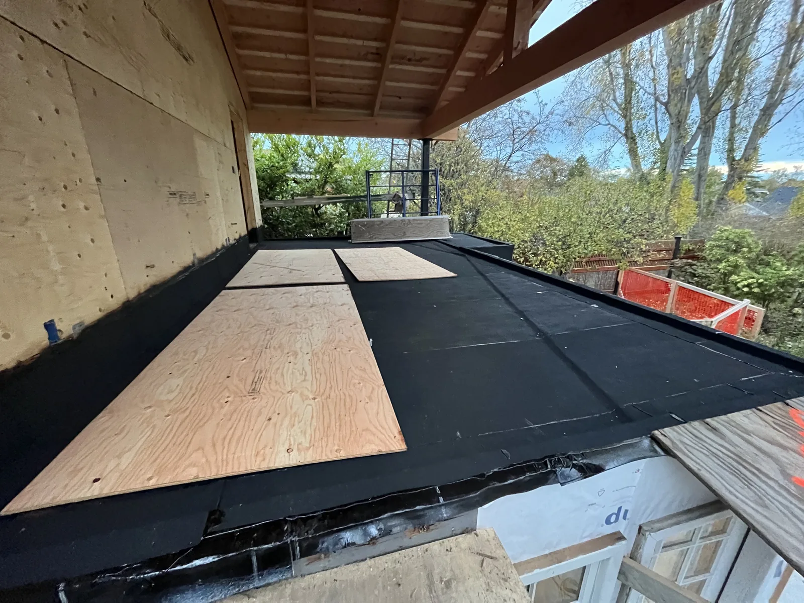 Flat roof membrane being laid over new sheathing