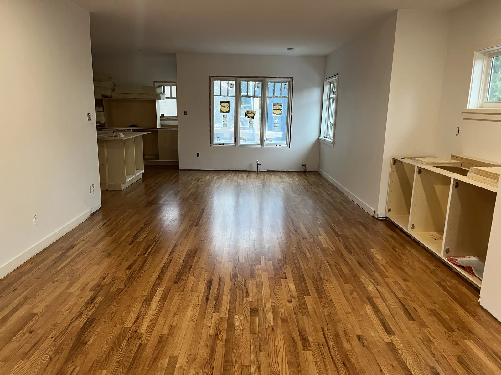 Empty living room with a refinished hardwood floor