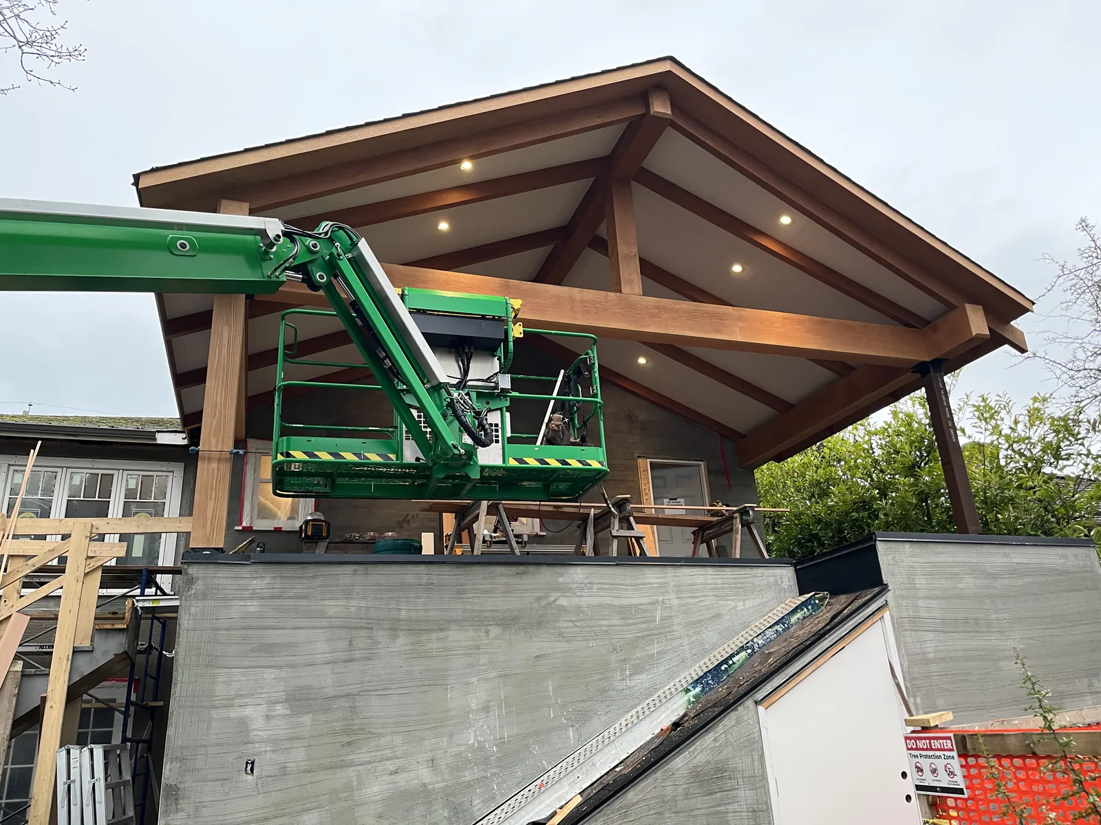 Heavy timber roof structure being set in place by a telehandler