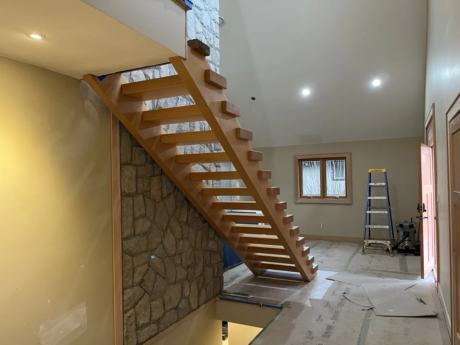 Open riser stair beside a stone feature wall