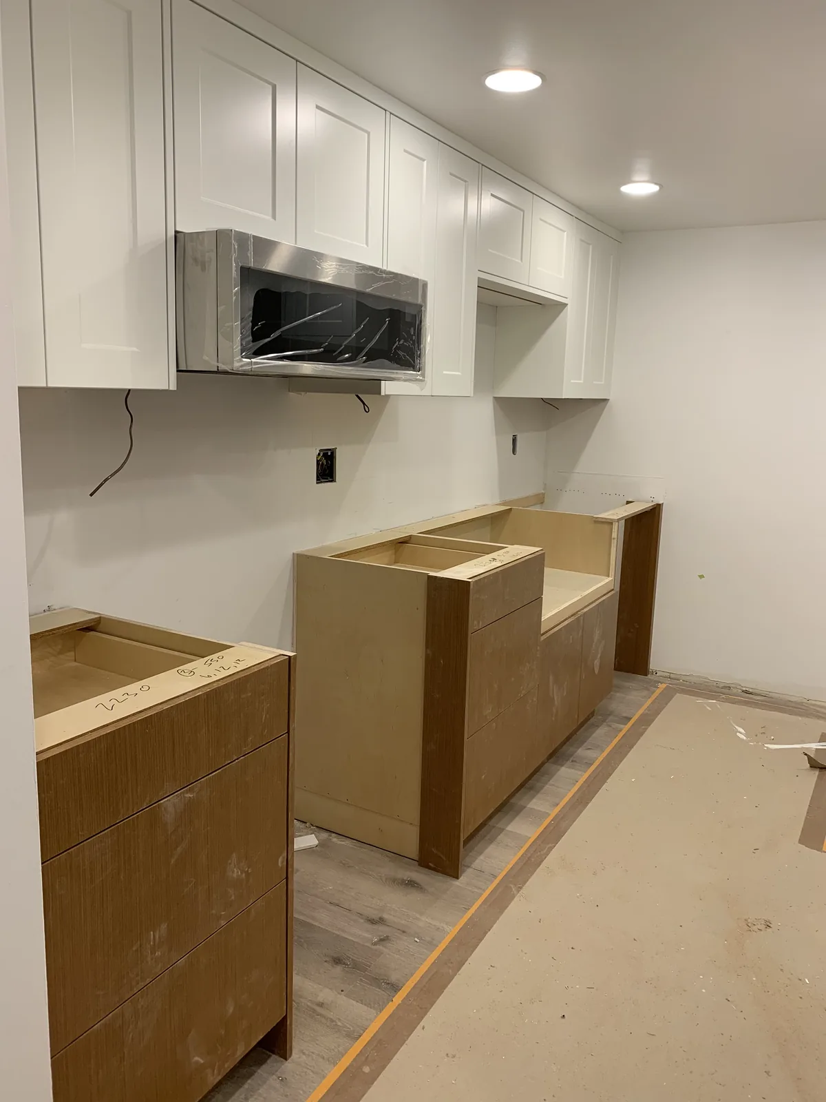 Kitchen cabinets being installed above a protected floor