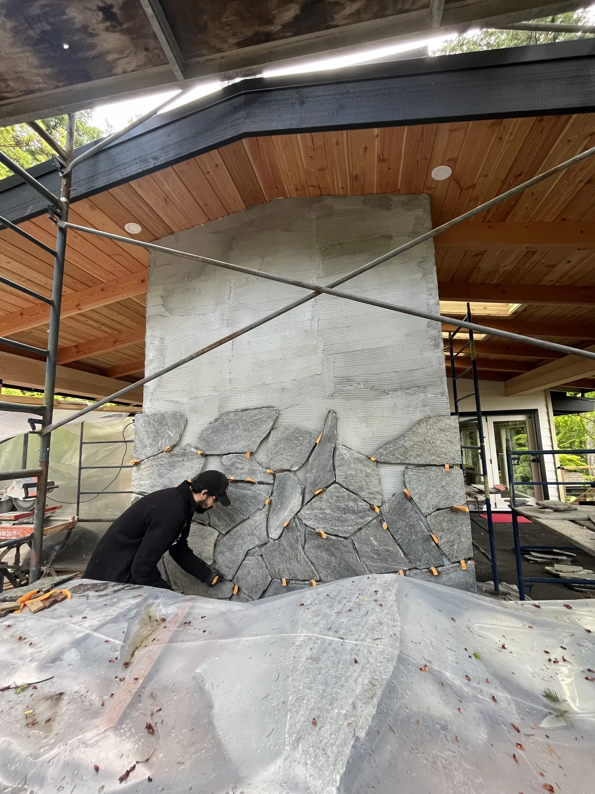 Stone chimney being built behind scaffolding