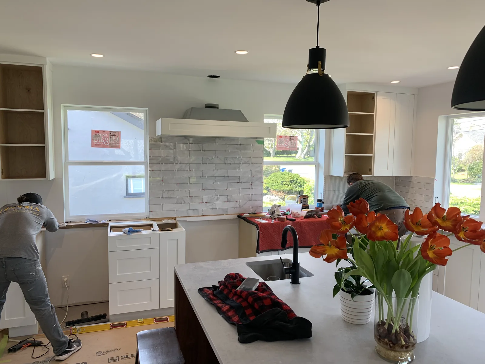 Kitchen with a large island, black pendant lights and a range hood