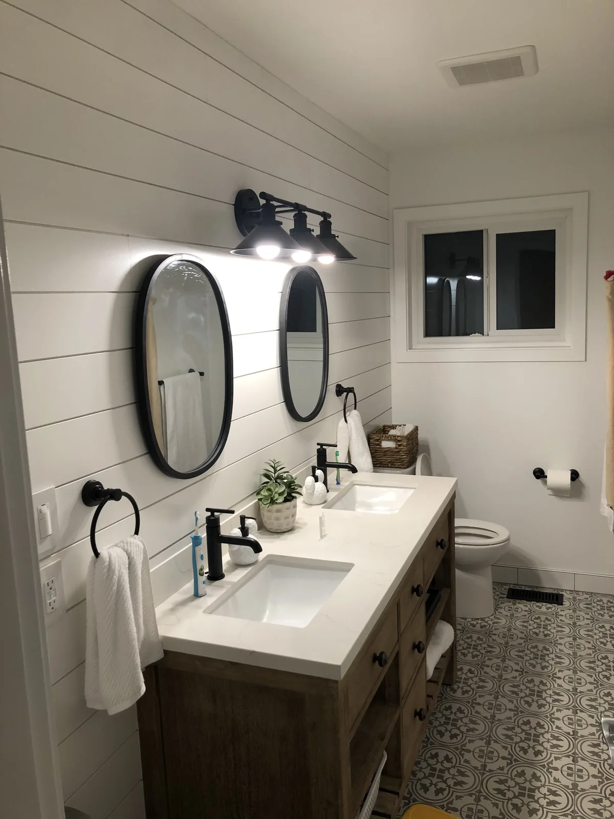 Bathroom with a double vanity, two round mirrors and patterned tile flooring
