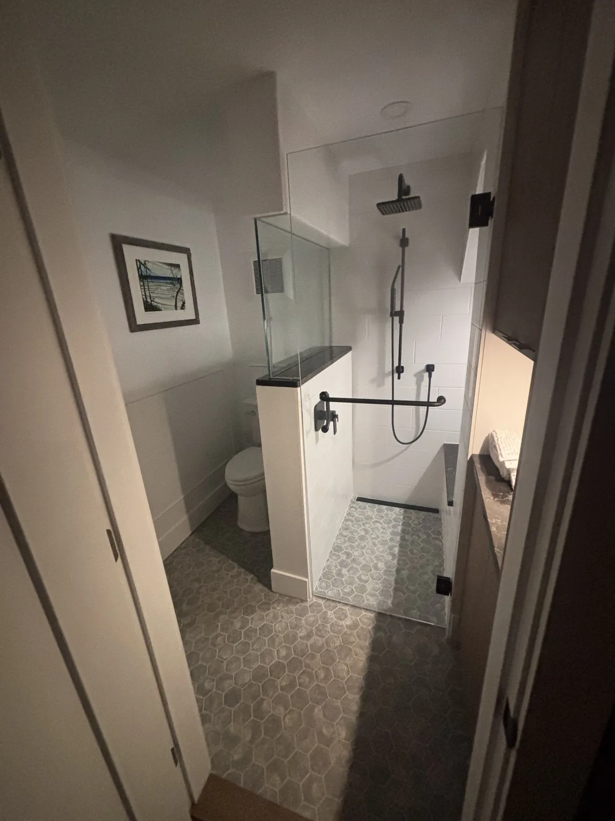 Walk in shower with pebble tile flooring seen through a doorway