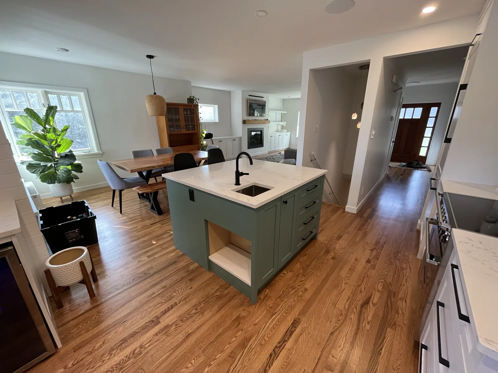 Open plan living room and kitchen with a green island and hardwood flooring