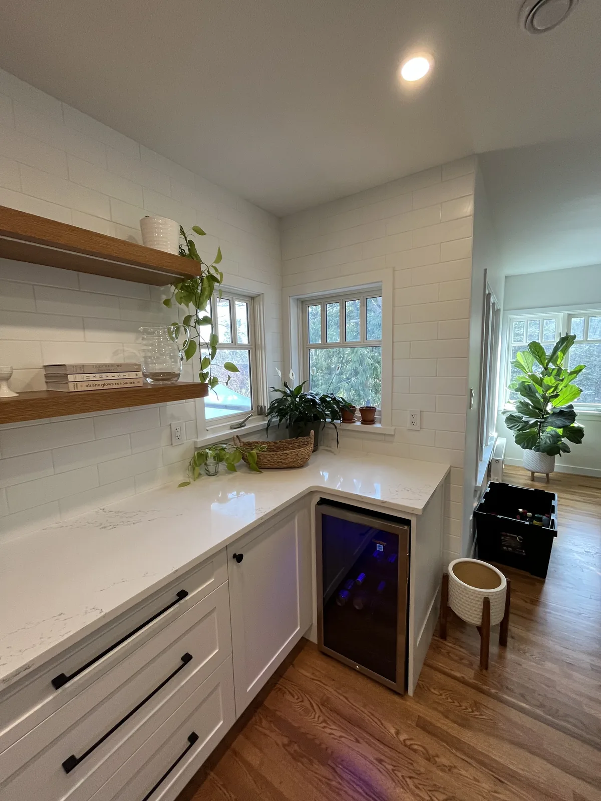Kitchen run with white drawer fronts, a wine fridge and a floating shelf