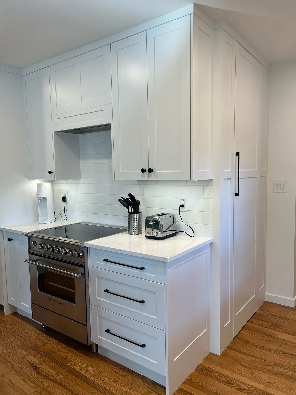 Kitchen with white shaker cabinets, a stainless range and hardwood flooring