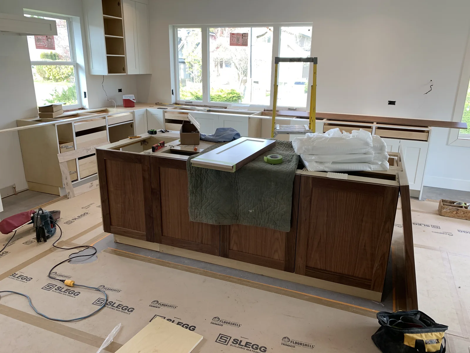 Walnut kitchen island being installed with the cabinets partly fitted