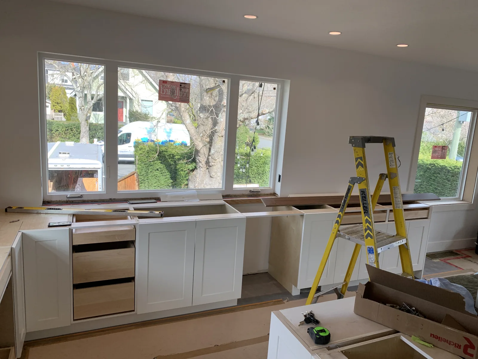 Kitchen cabinets and drawer units being installed under a window