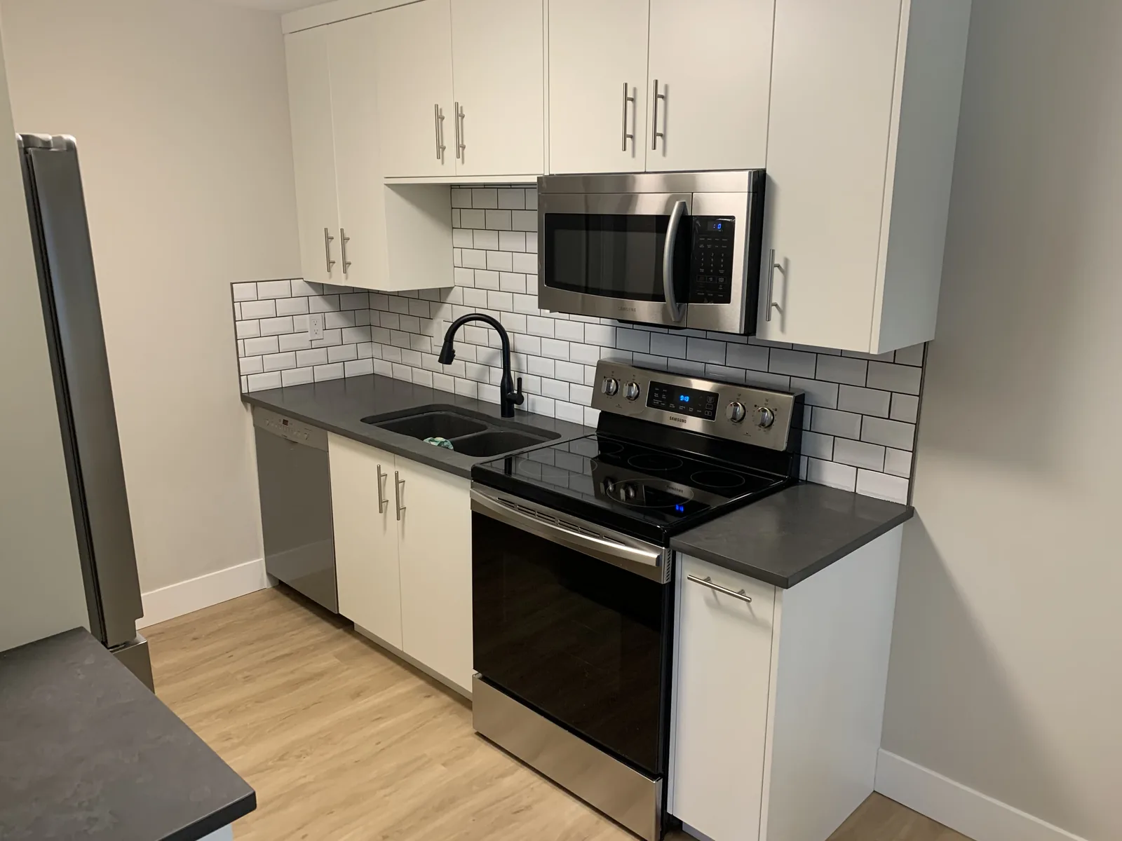 Kitchen with a subway tile backsplash, range and microwave