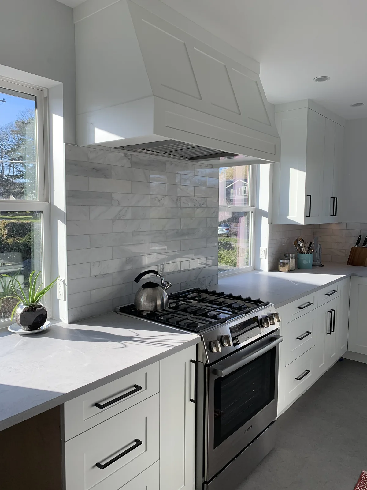 Kitchen with a gas range, white cabinets and a marble countertop