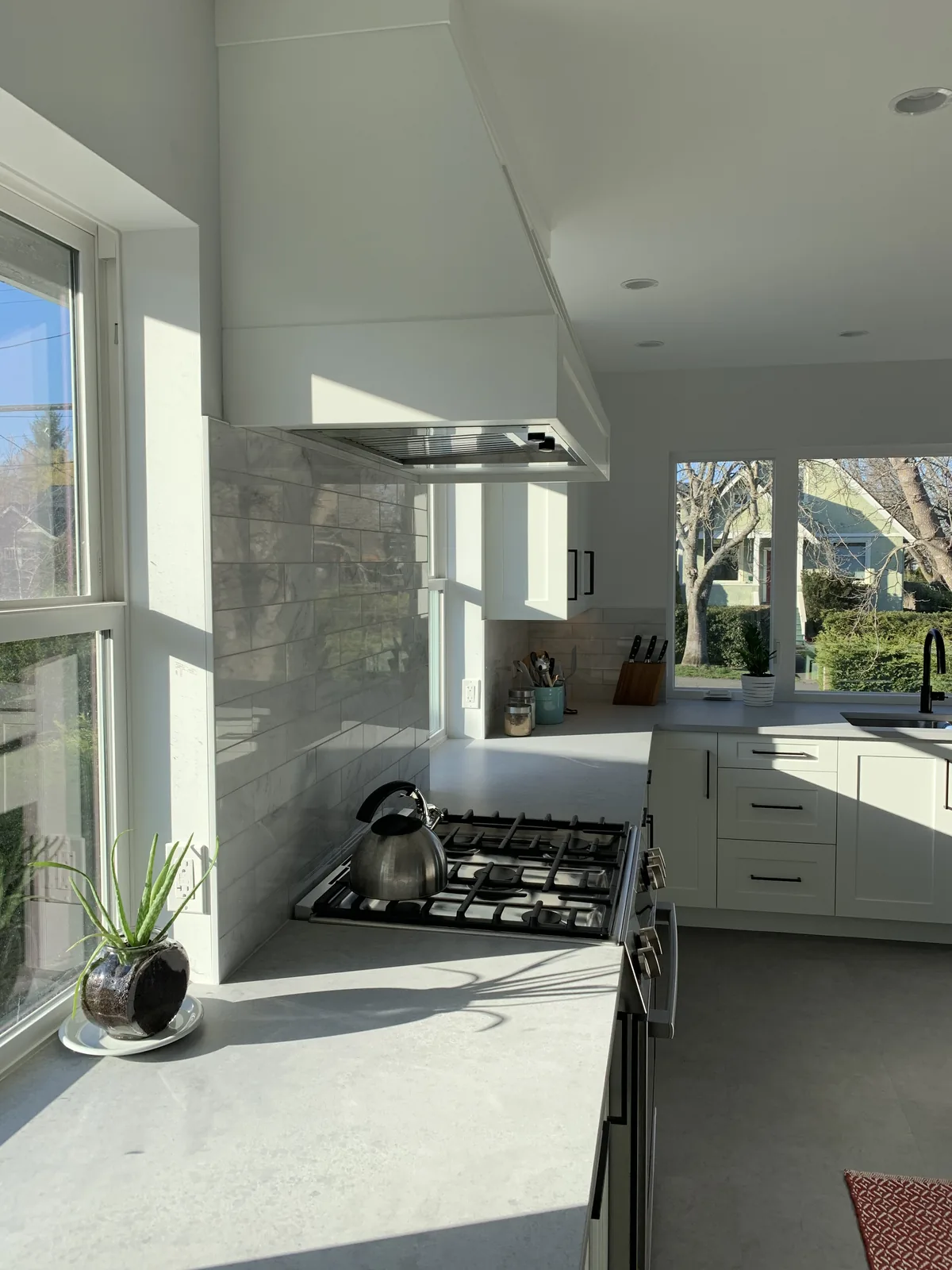 Gas range and marble backsplash beside a window