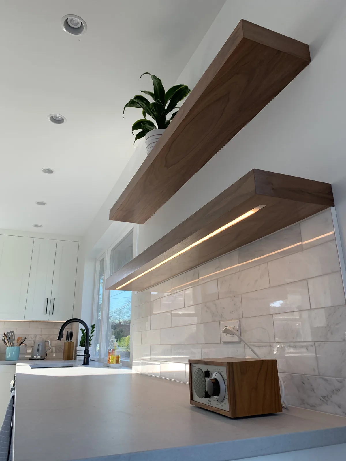 Wood floating shelves above a marble backsplash