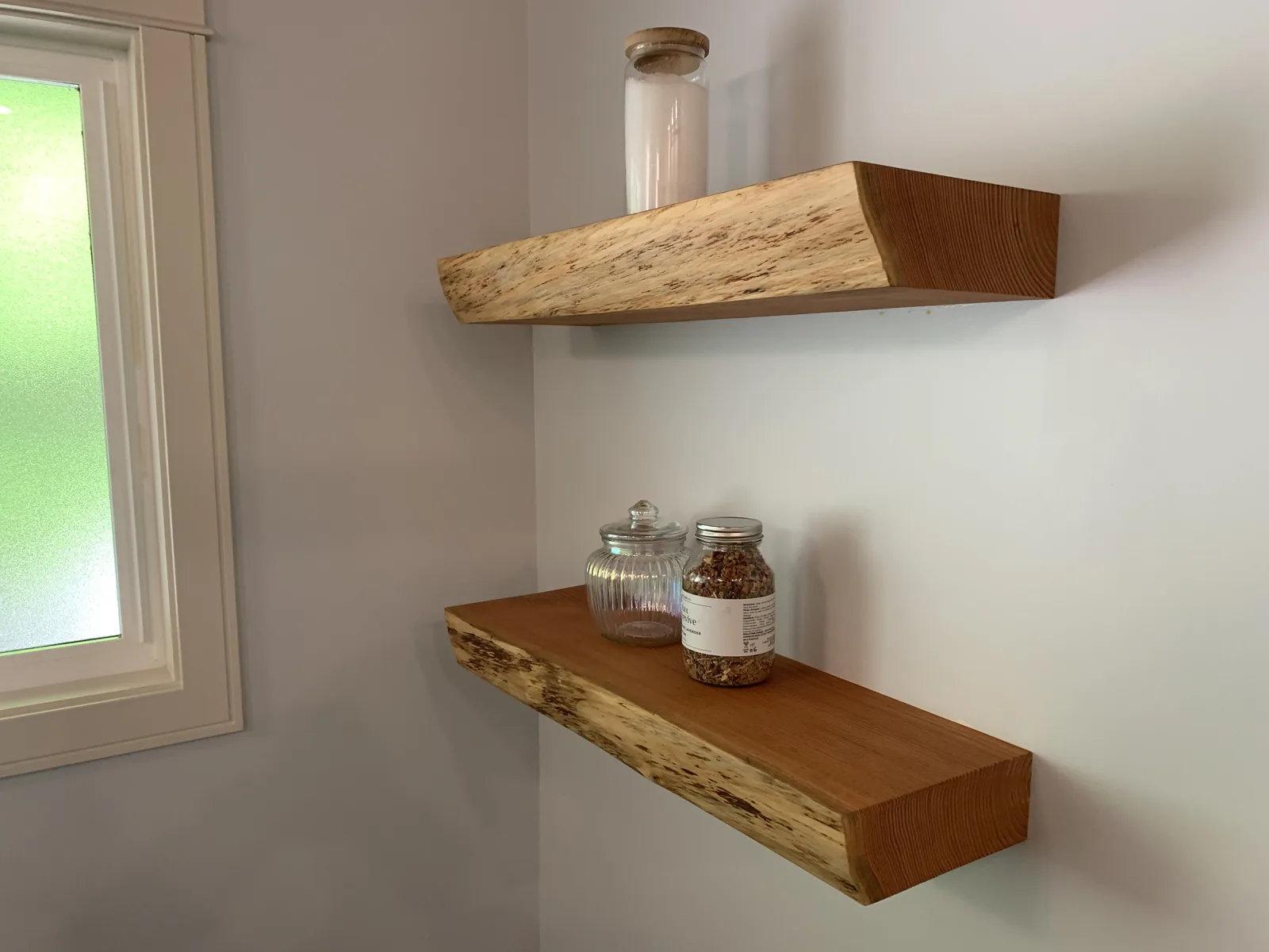 Live edge wood floating shelves beside a window