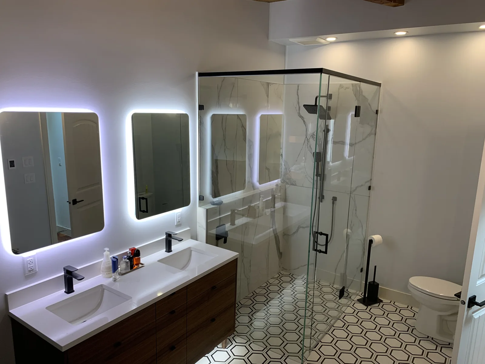 Bathroom with a glass shower, double vanity and backlit mirrors