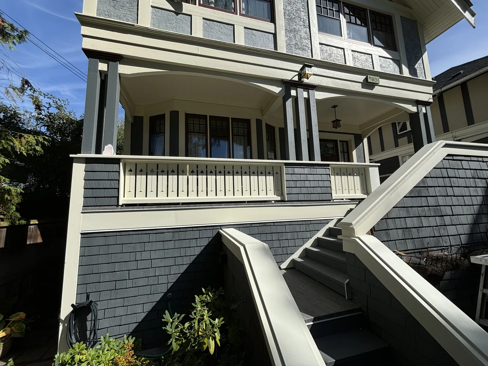 Grey shingled character home exterior with white railings and rebuilt stairs