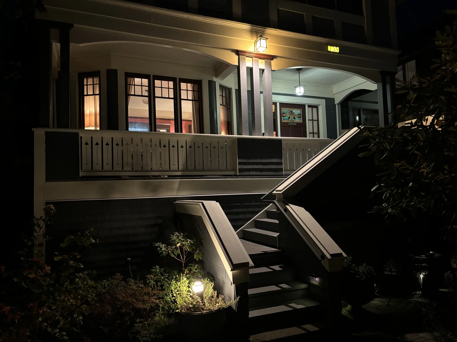 Covered porch and rebuilt front stairs of a character home lit at dusk, completed by DM Patterson Construction